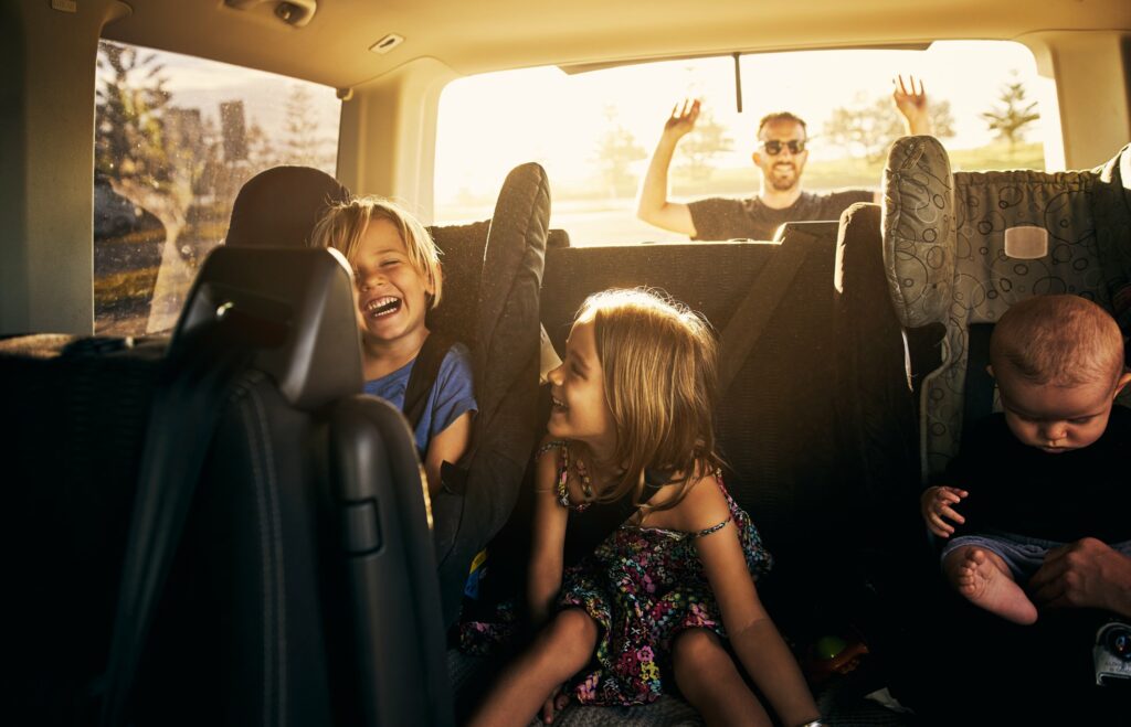 Iloisia lapsia Solarplexius-tummennuksilla varustetun auton takapenkillä.