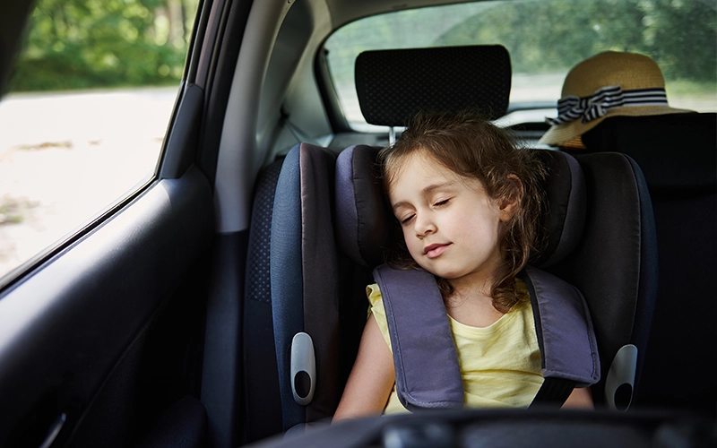 pikkutyttö nukkuu auton takapenkillä ilman tummennusta ikkunassa 
